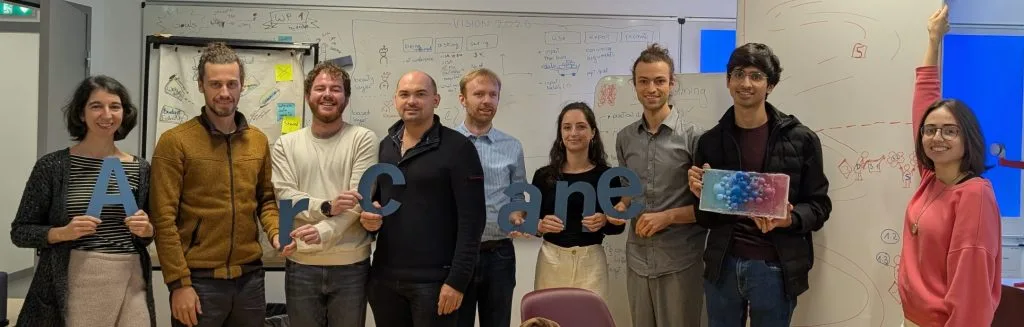 Multiple people standing infront of a white board.